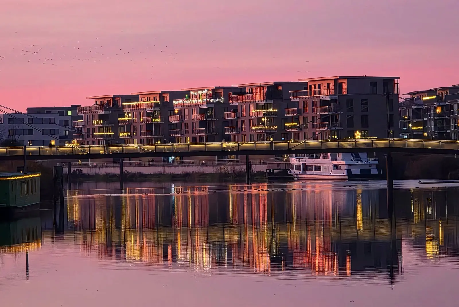 Hafenansicht mit leuchtender Uferpromenade im Abendrot